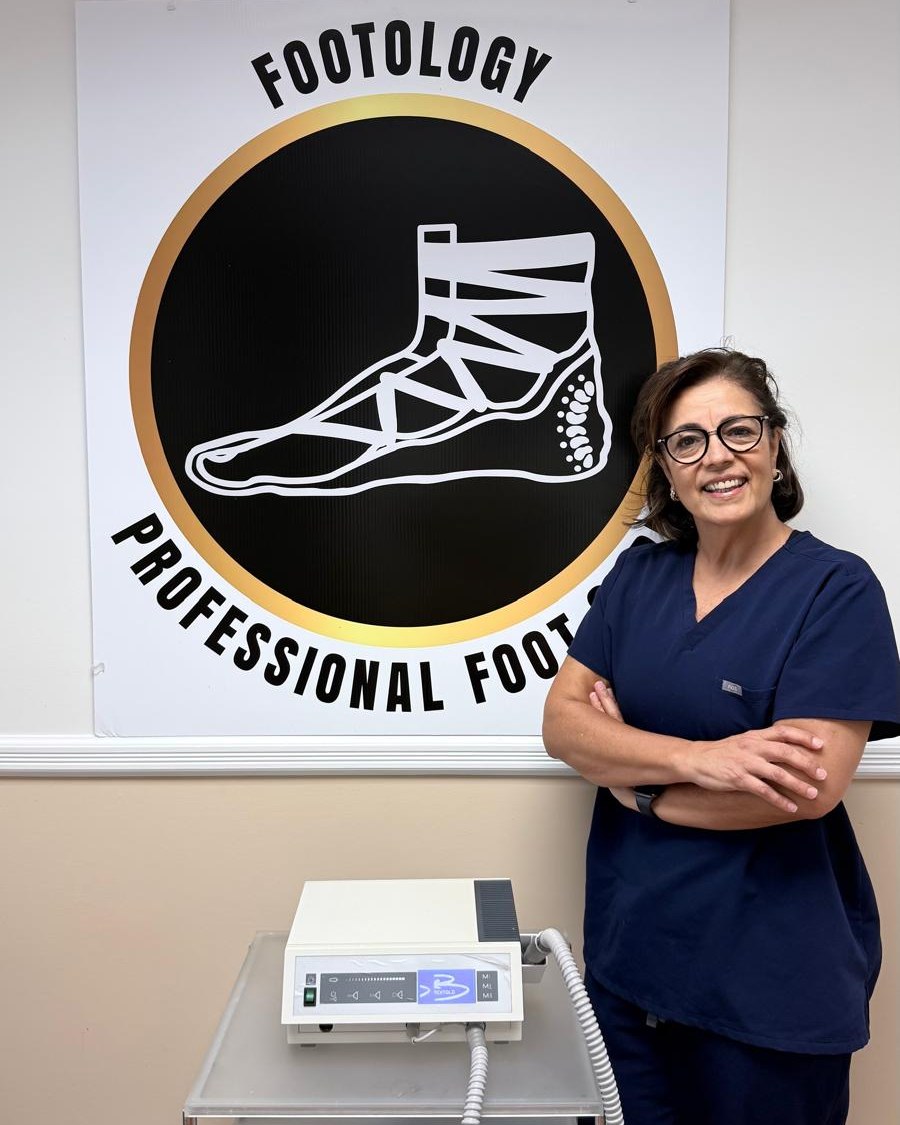 Ana Maria Anselmo standing beside the Footology logo at her studio